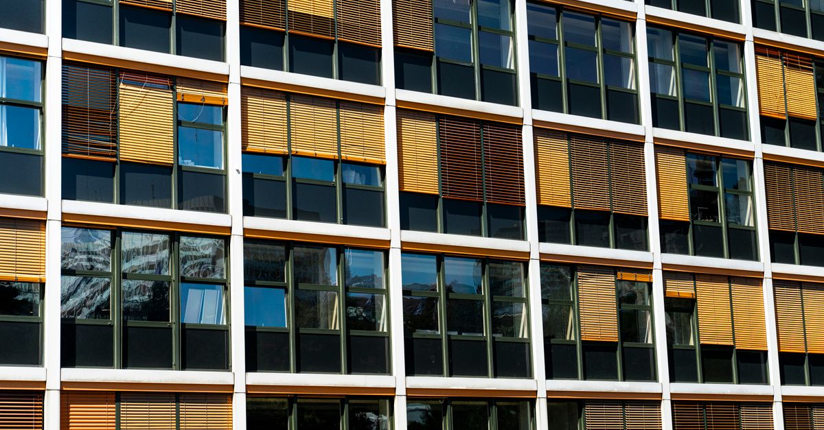 Contemporary glass facade of an office building in Lausanne, Switzerland, showcasing reflections and sunlight.