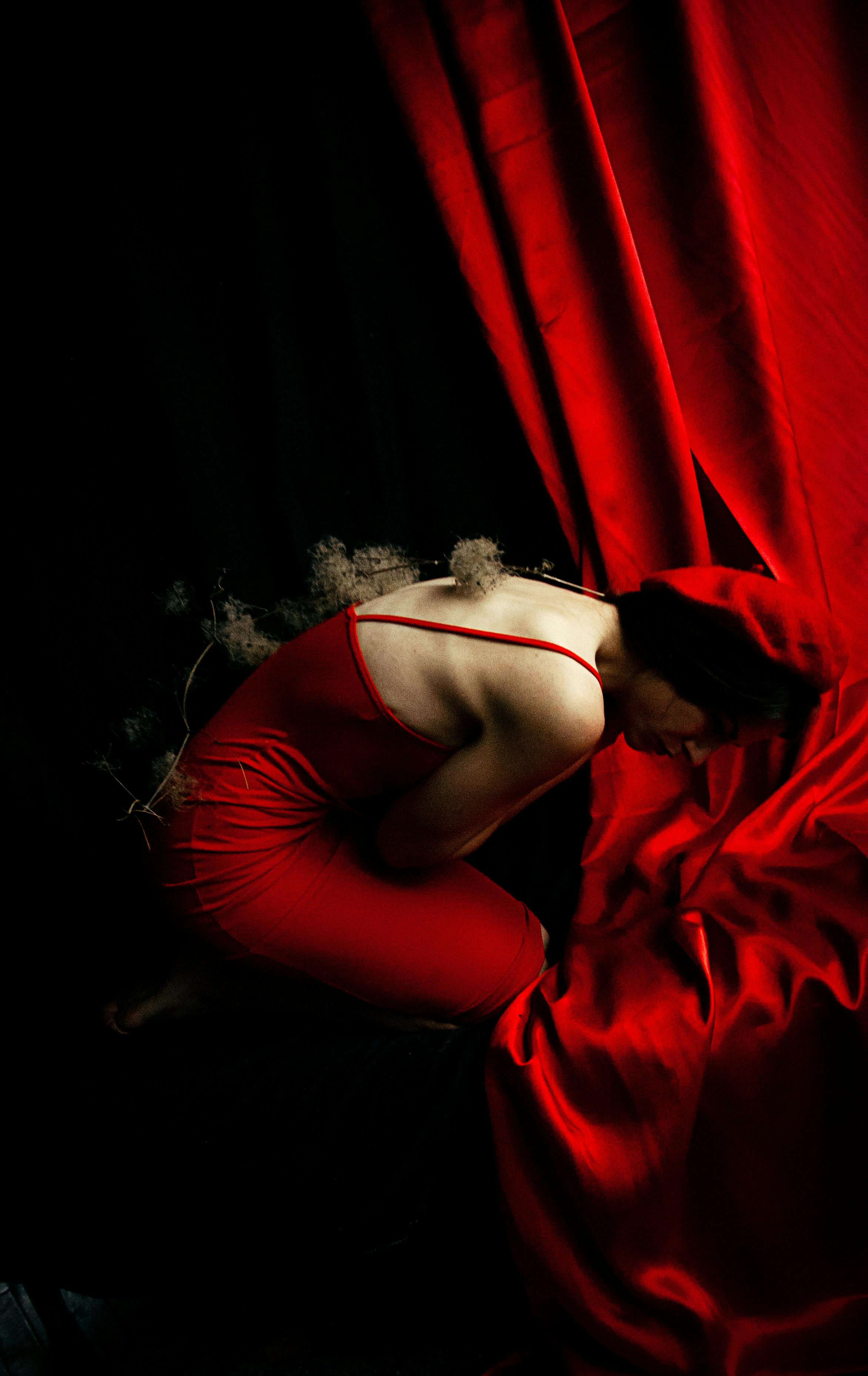 grátis Mulher De Vestido Vermelho Sentada Sob Cortina Vermelha Foto profissional