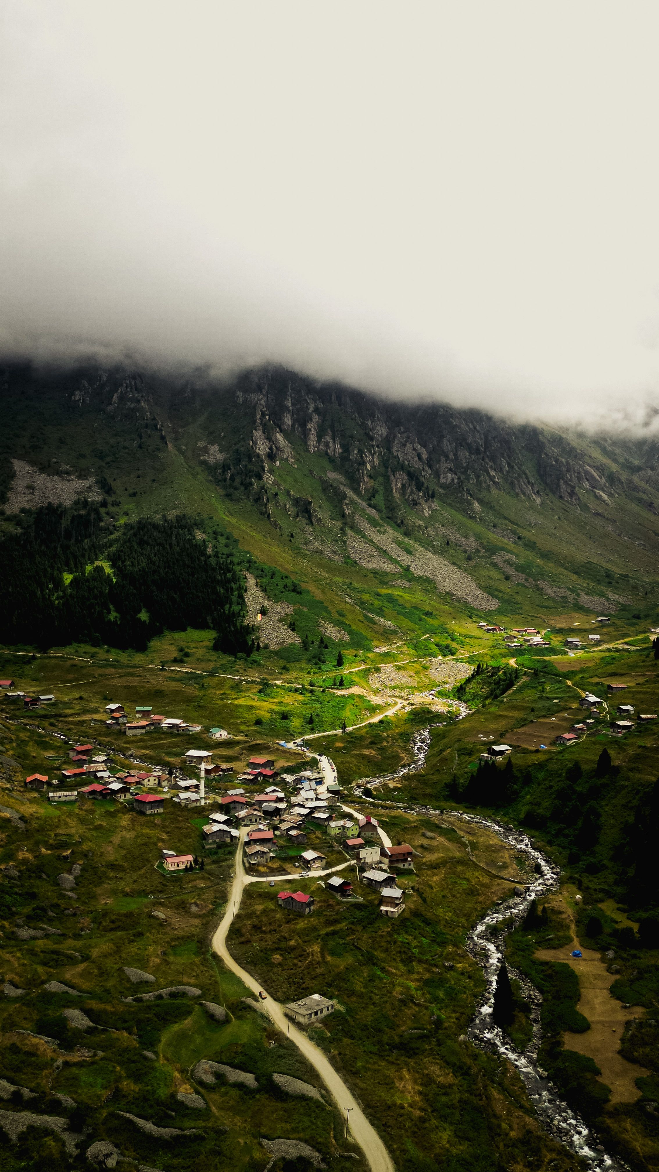 A picturesque village nestled in a lush green valley beneath misty mountains, creating a serene rural landscape.
