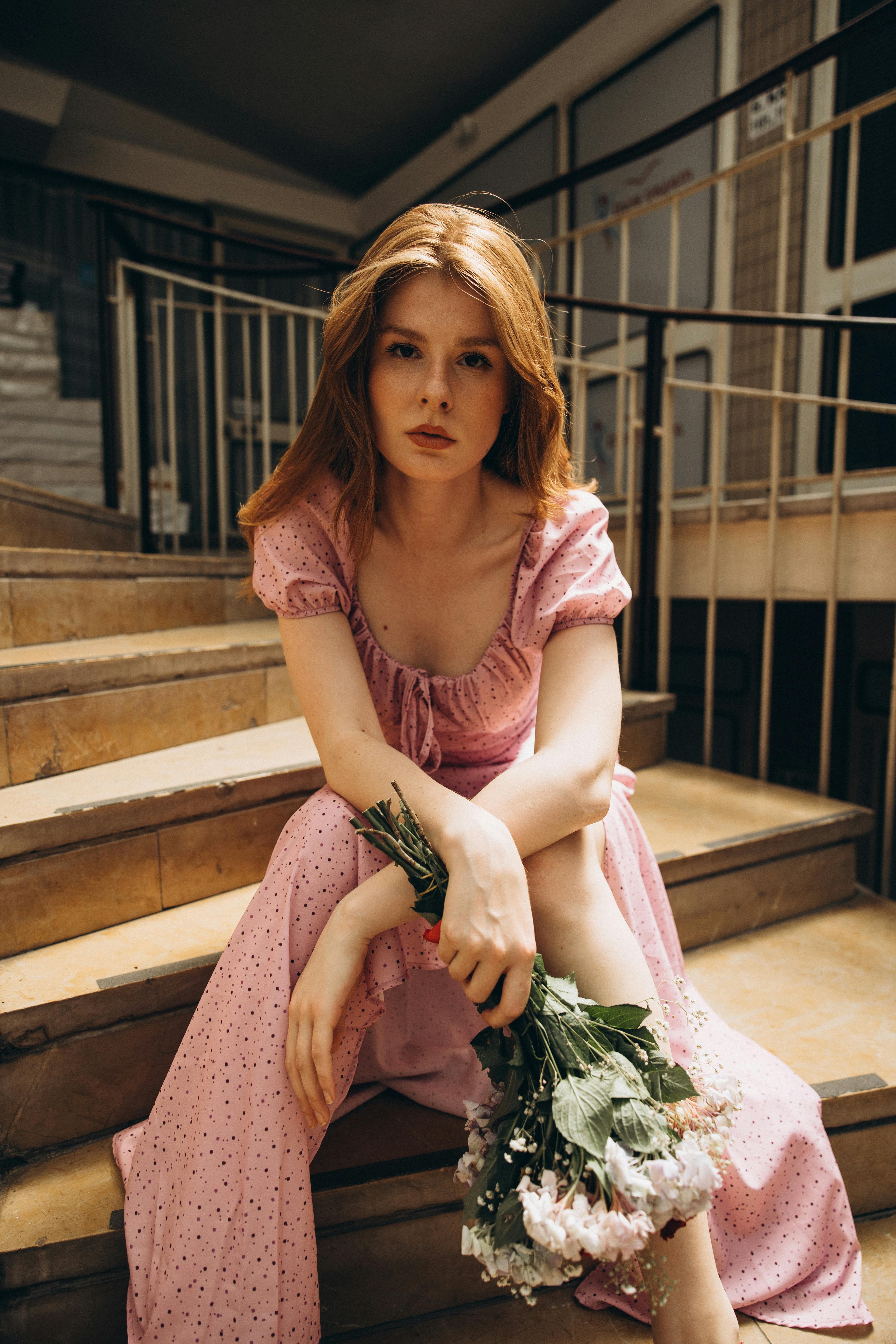 a woman in a pink dress sitting on some stairs