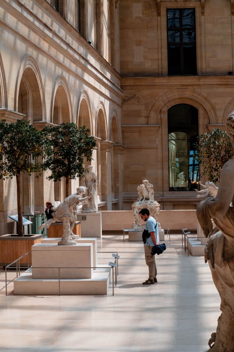 Man Visiting Louvre In France And Looking On Statue