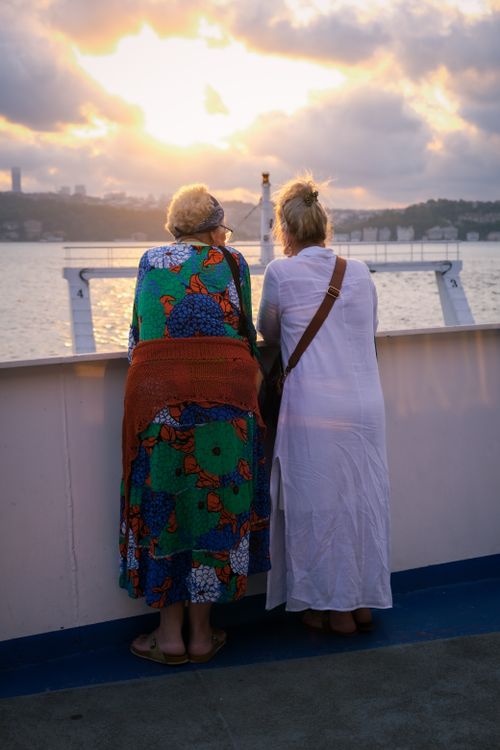 Free Two women admiring a beautiful sunset over the sea during a ferry journey. Stock Photo