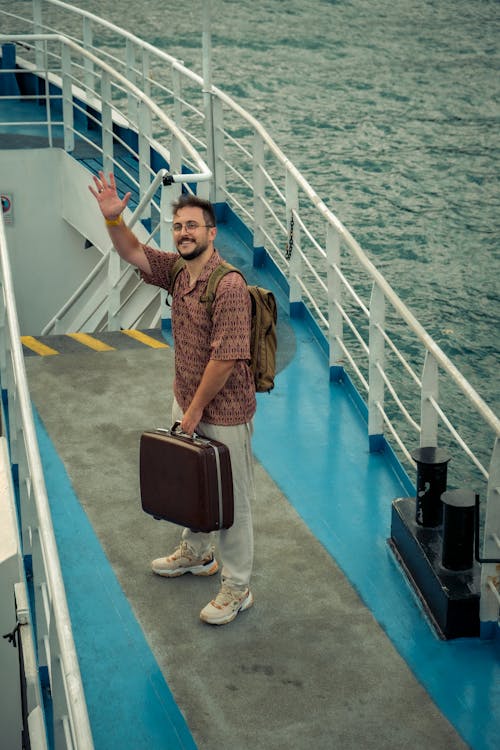 Free Standing Man with Suitcase in Hand Waving Hand on Farewell Stock Photo