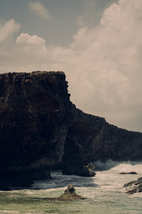 View of Waves Crashing on a Rocky Shore and a Cliff 