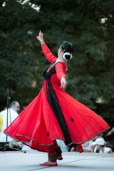 A captivating dance performance by a woman in a red dress at an outdoor event.