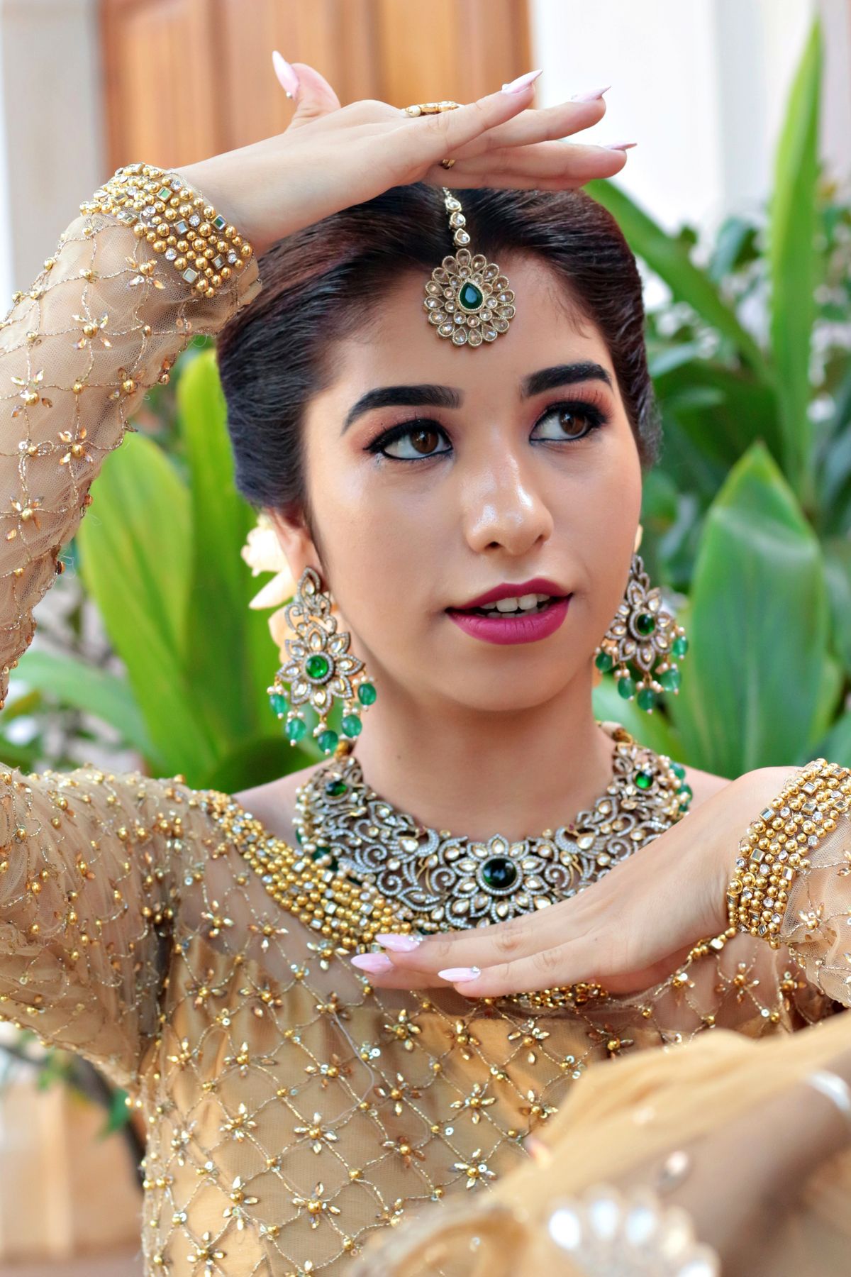 Indian fashion model in editorial portrait wearing long emerald drop earrings