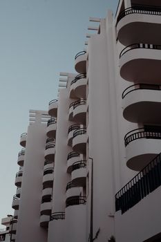 Low angle view of a modern urban apartment building with curving balconies against a clear blue sky.