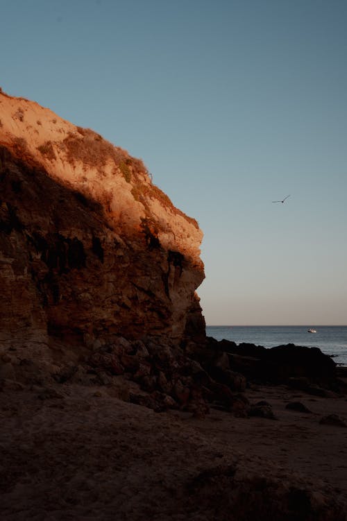 View of a Rocky Cliff on a Shore under a Clear Sky 