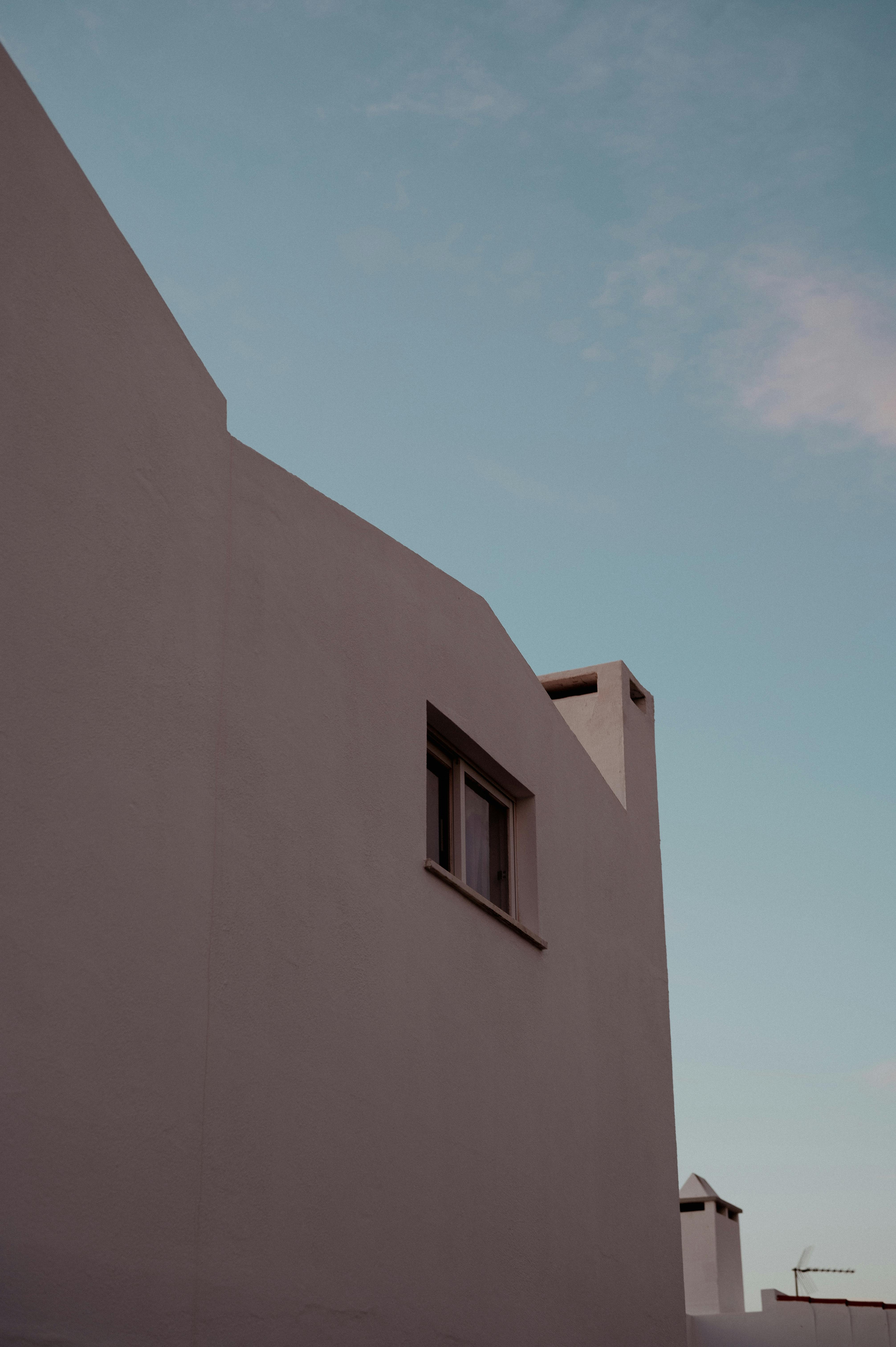 Free A modern building facade with simplistic lines against a clear blue sky, showcasing minimalist architecture. Stock Photo