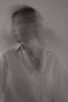 Black and white blurred motion portrait of a woman in a shirt, creating an artistic and mysterious vibe.