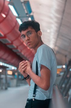 在城市室内，时尚的年轻人戴着眼镜，系着背带，摆出休闲的姿势