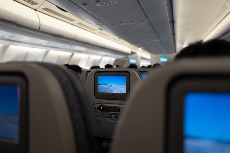 Interior Of A Passenger Plane With Screens On The Backs Of The Seats