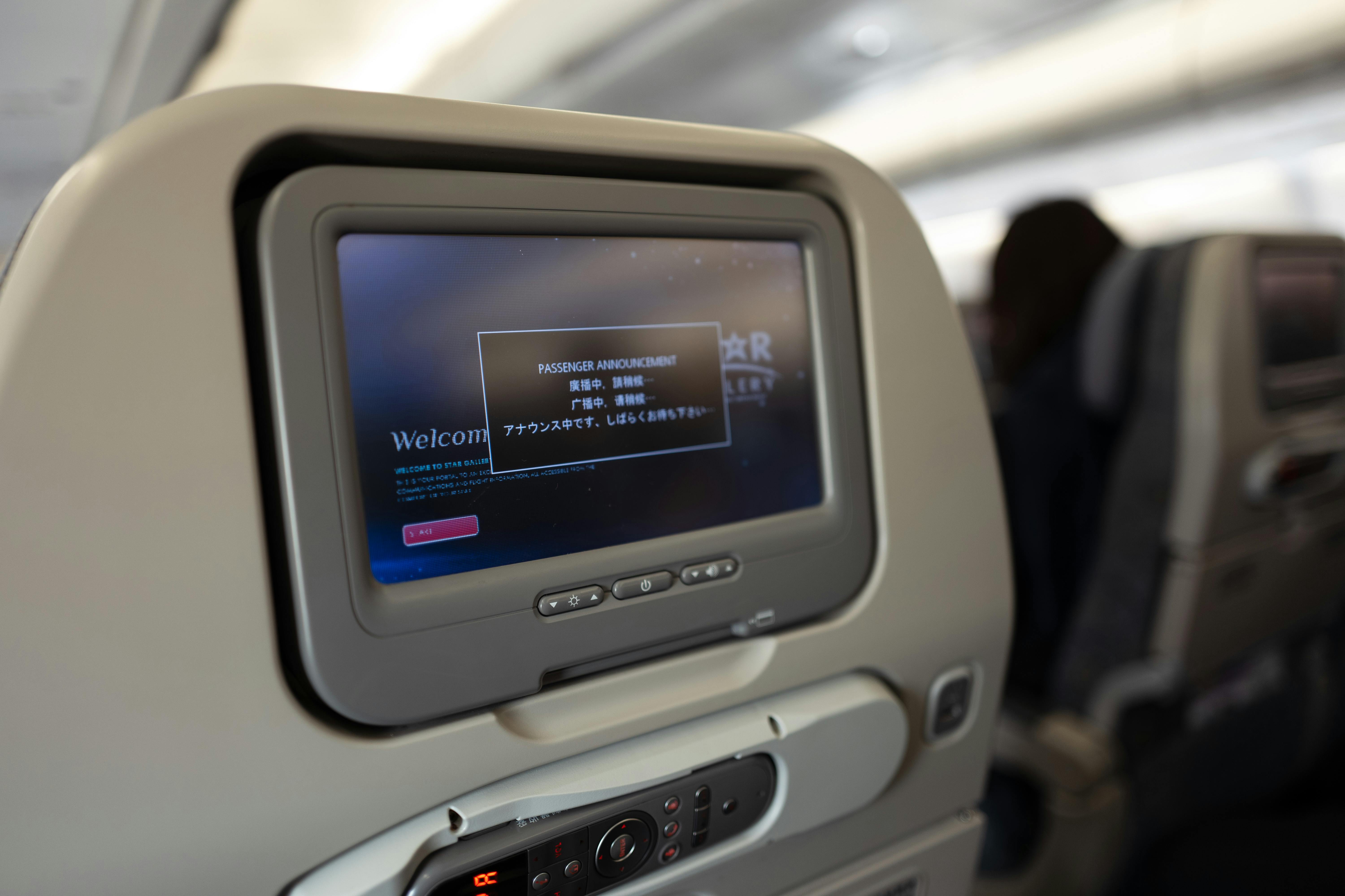 Airplane passenger seat screen showing a passenger announcement onboard.