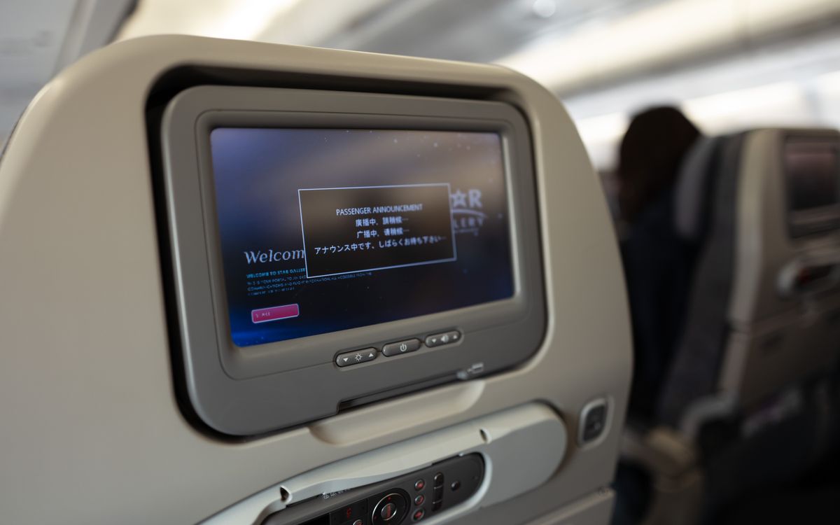 Airplane passenger seat screen showing a passenger announcement onboard.