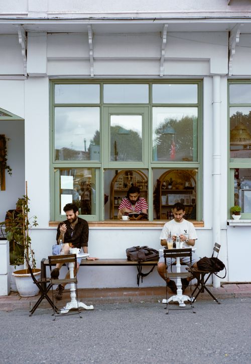 Free Three men sit outside a cafe in Istanbul, Türkiye, enjoying coffee on a bustling city street. Stock Photo