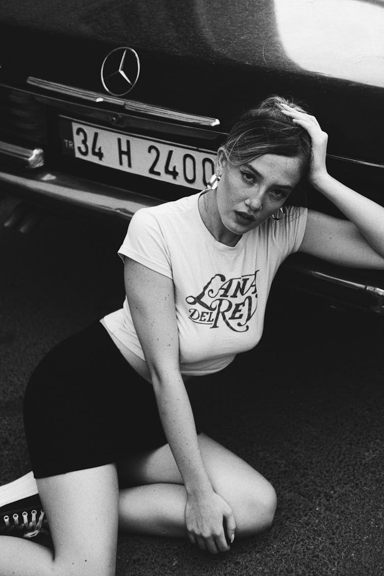 Model In A Lana Del Rey Top And Mini Skirt Sitting In The Street Behind A Car