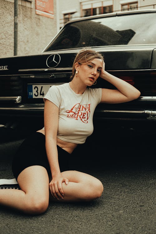 Model in a Crop Top and Mini Skirt Sitting in the Street Behind an Old Black Mercedes