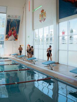 A group of adults preparing to swim in an indoor pool, showcasing a lively aquatic environment.