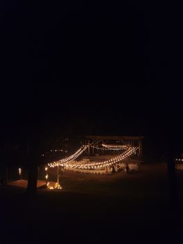 A cozy nighttime outdoor gathering with string lights creating a warm and inviting atmosphere.