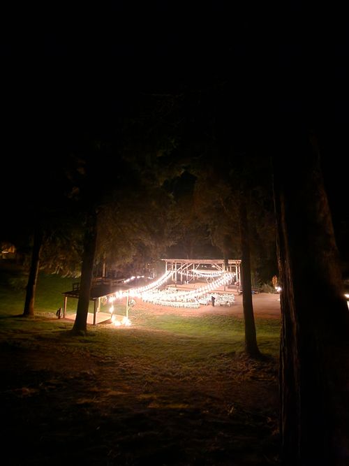 Free Outdoor venue with glowing lights and wooden stage under night sky, creating a magical atmosphere. Stock Photo