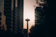 在西雅图的日落时分，太空针塔从现代摩天大楼中穿出其框架