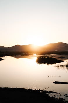Captivating sunrise over a tranquil lake reflecting surrounding mountains, perfect for nature lovers.