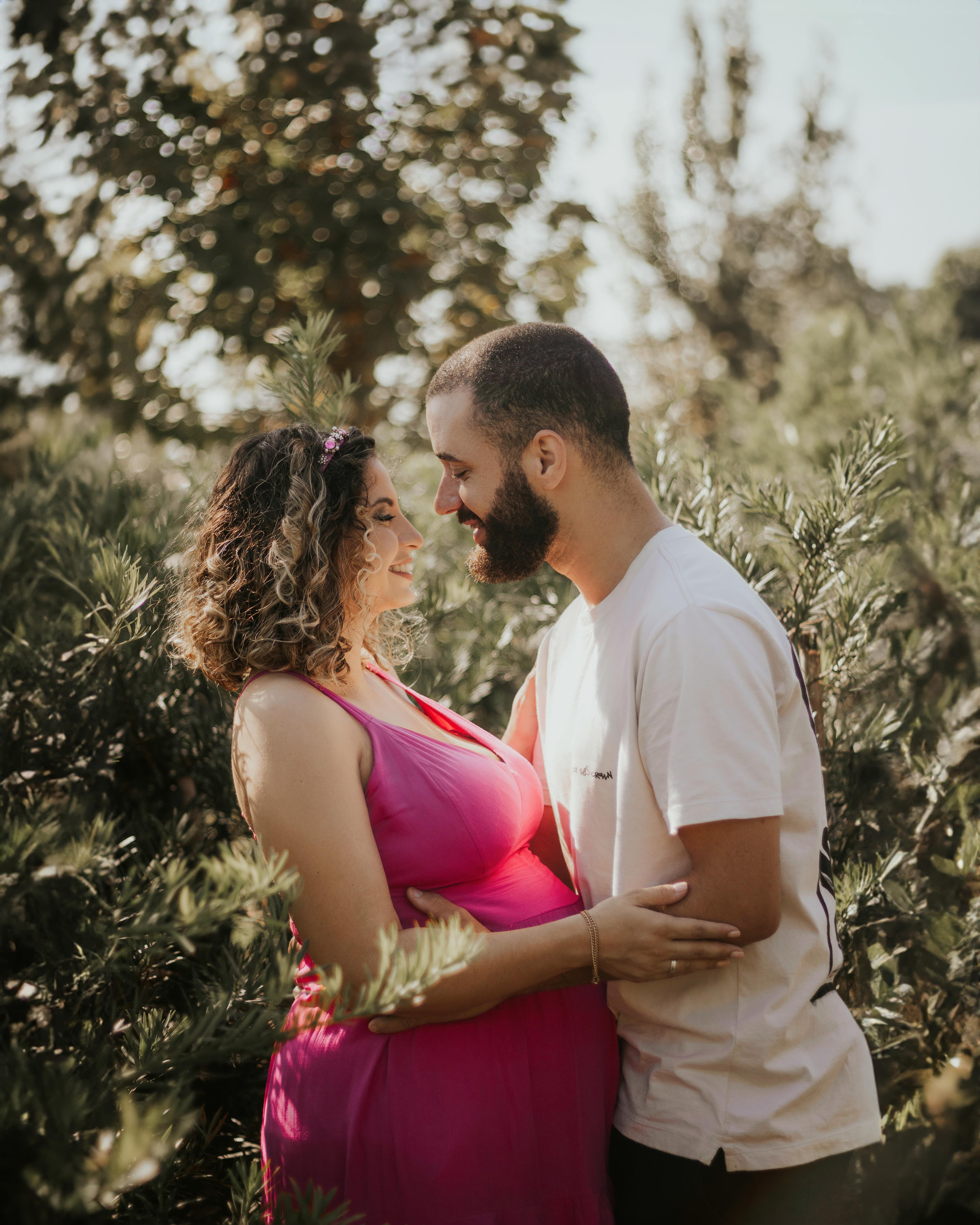 A loving couple embraces in nature during a maternity photo session.