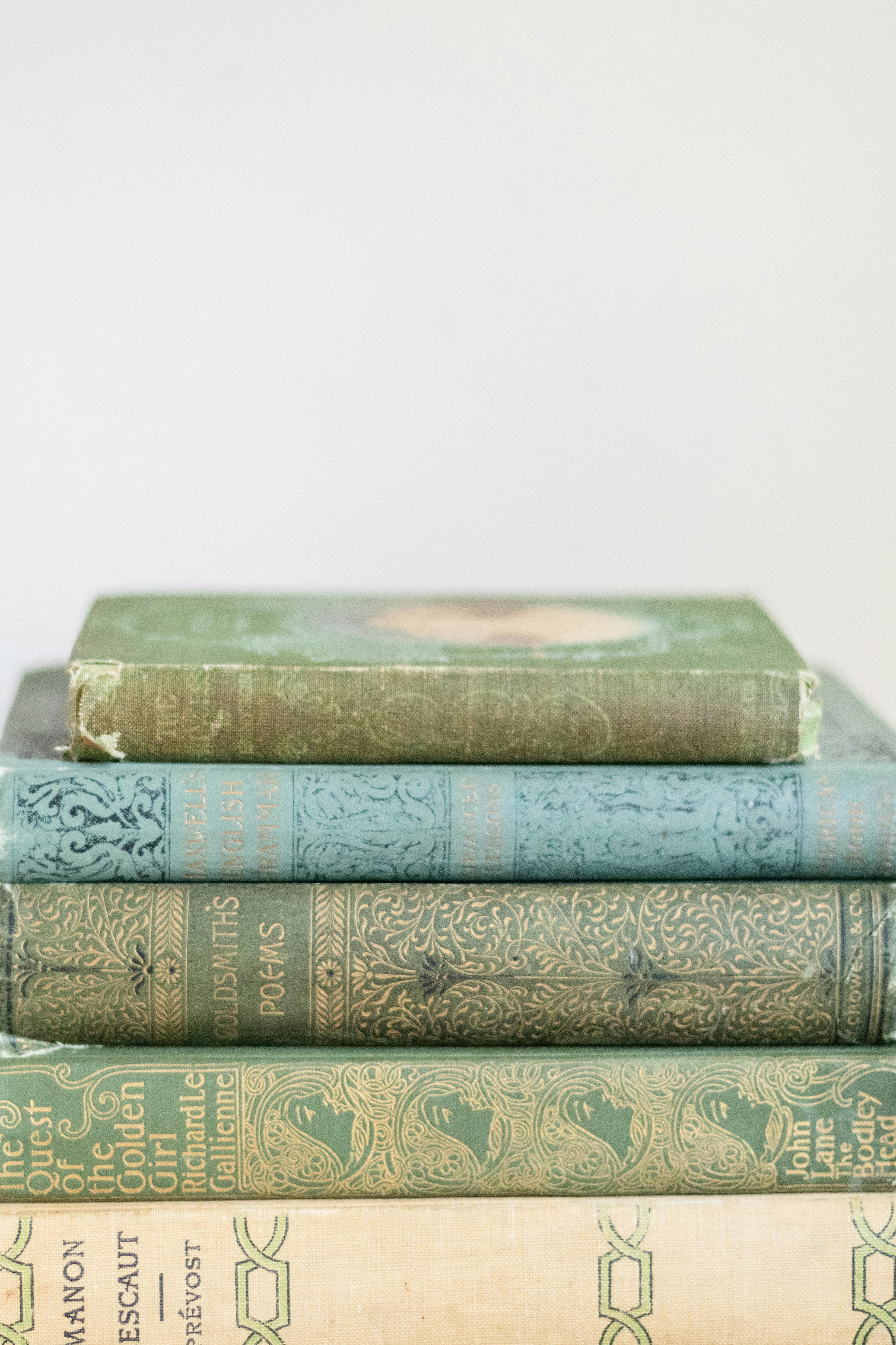 A pile of antique books with ornate bindings on a soft-focus background.