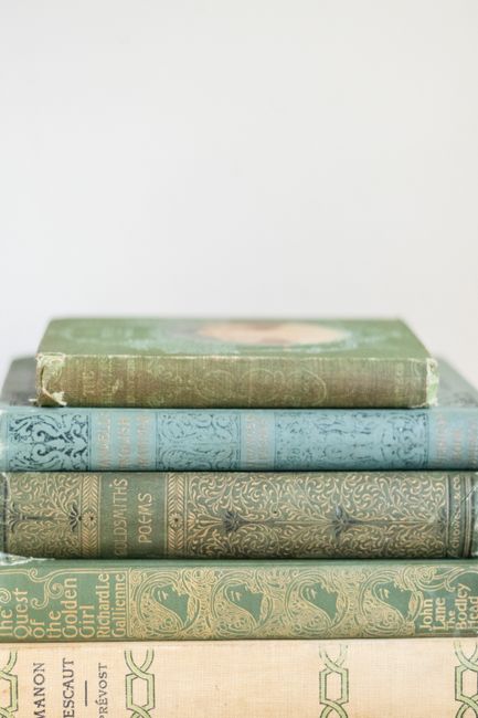 A pile of antique books with ornate bindings on a soft-focus background.