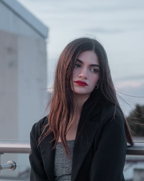 Free Stylish woman with red lipstick in an outdoor setting wearing a black jacket. Stock Photo