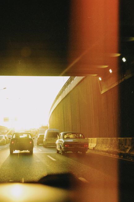 Cars driving through a city tunnel during sunset, casting a warm glow on the road.
