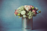 银罐中摆放着一束美丽的鲜花，背景是柔和的蓝色