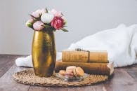 这幅乡村静物作品描绘了木桌上的花瓶、马卡龙和古董书