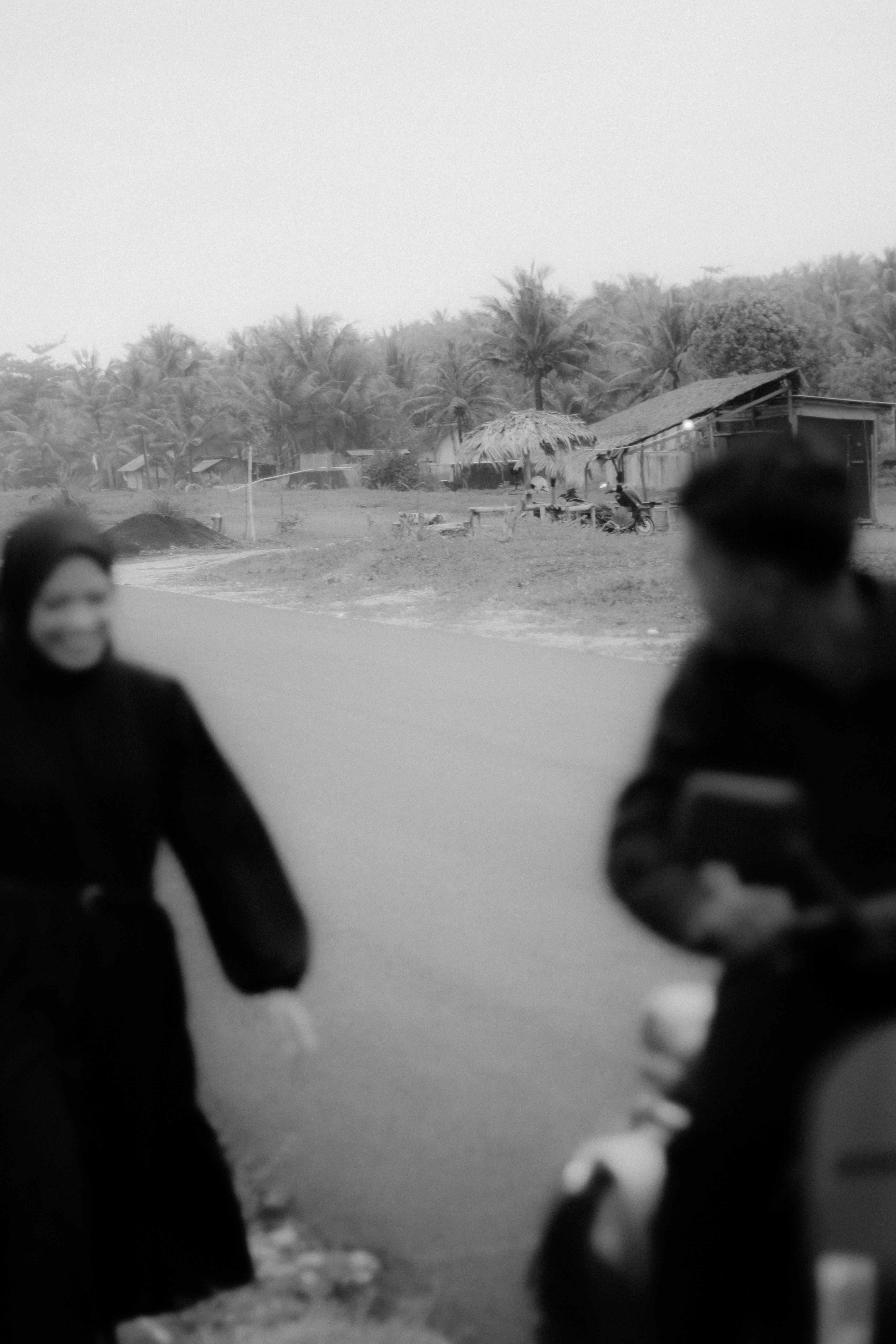 Black and white photo capturing motion blur of people on a rural road.