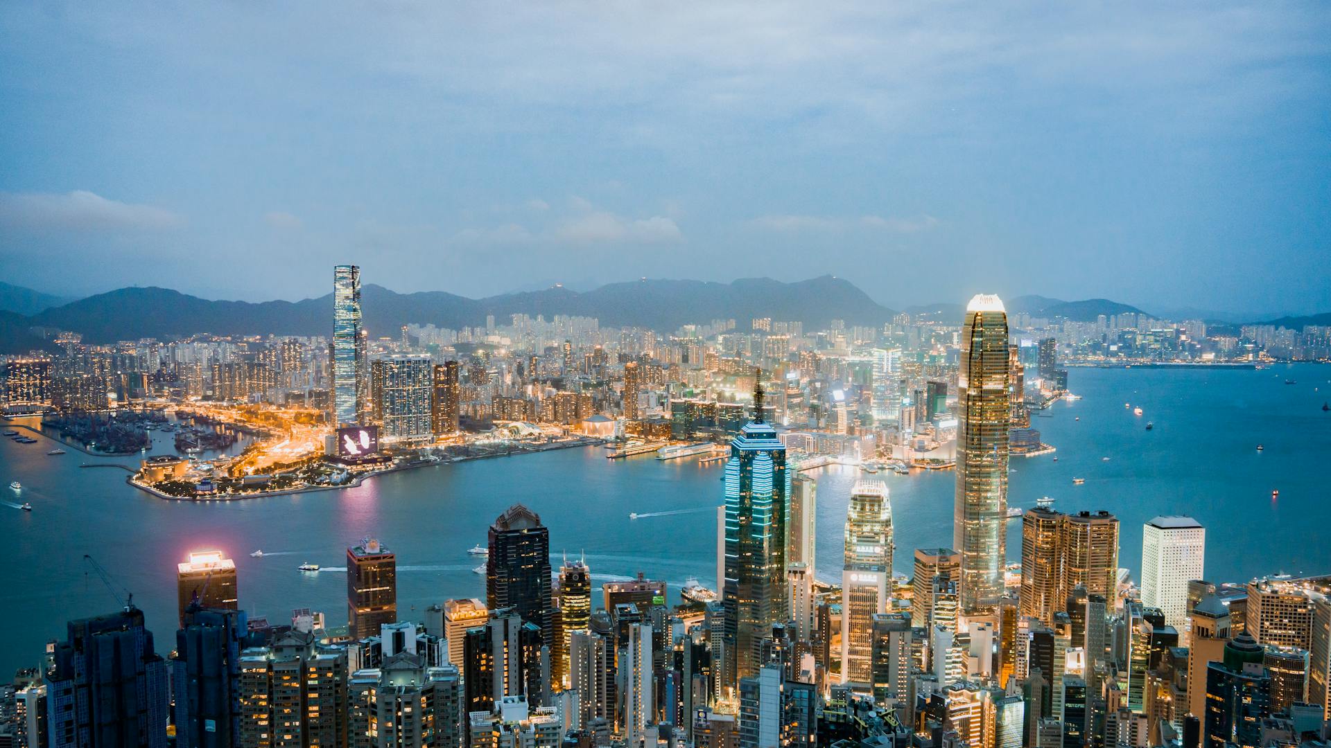 Explore the breathtaking skyline of Hong Kong at dusk, highlighting vibrant lights and Victoria Harbor.