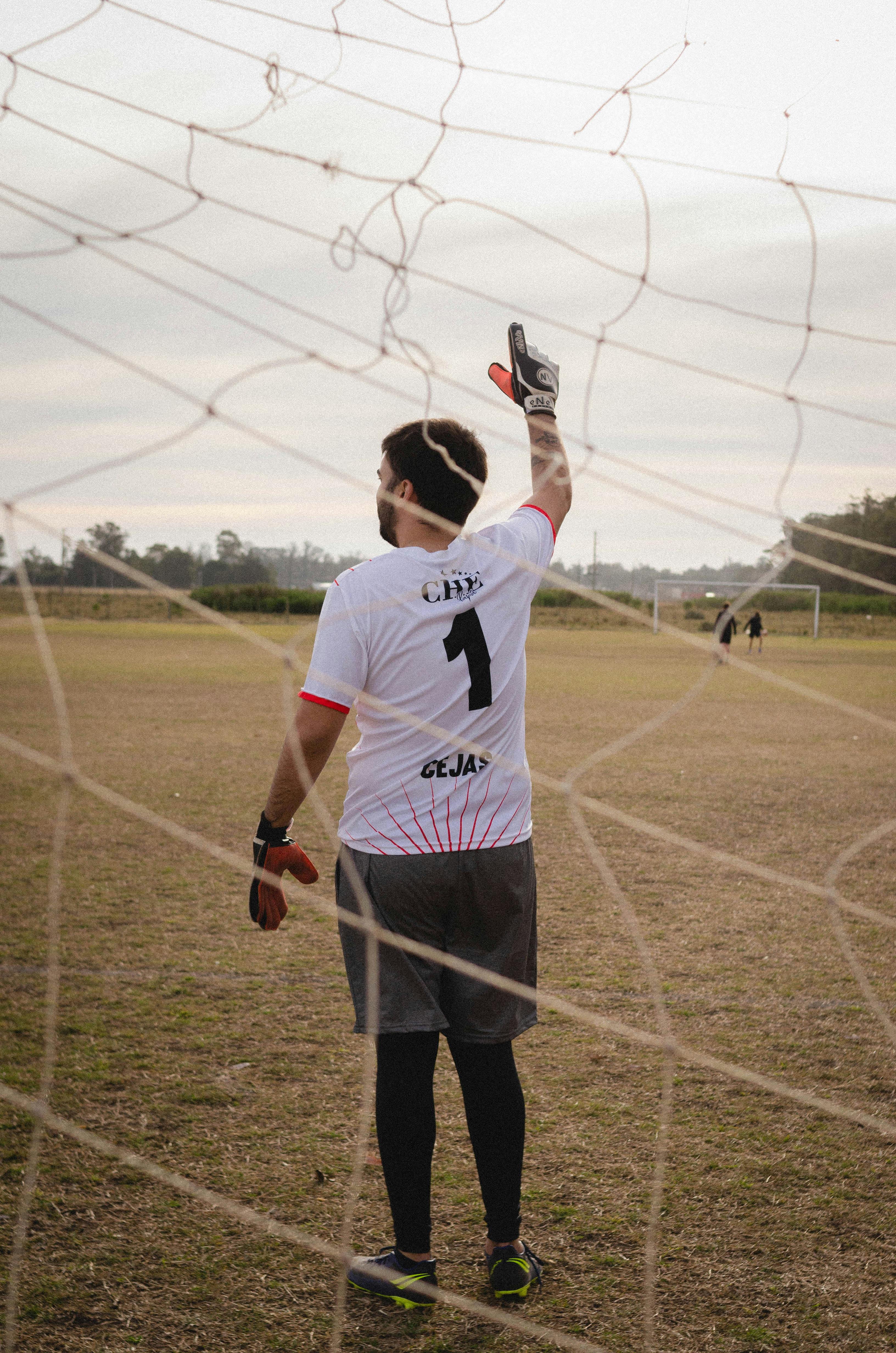 Back view of a goalkeeper gesturing during a soccer game on an open field.