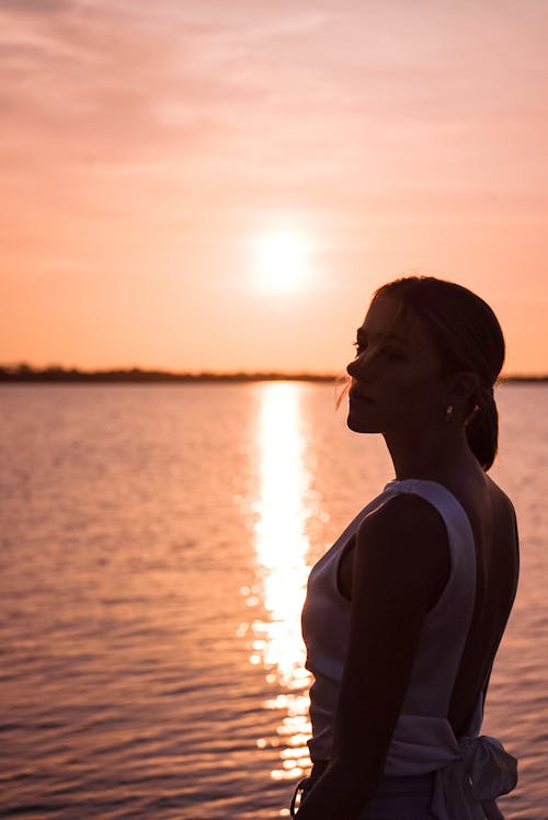 Woman Standing on Sea Shore at Sunset