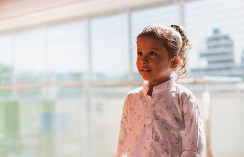 Free Charming portrait of a young girl in sunlight, wearing a white blouse, indoors. Stock Photo