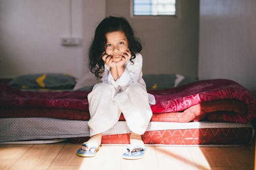 Little Girl in Pajamas Sitting on a Floor Bed