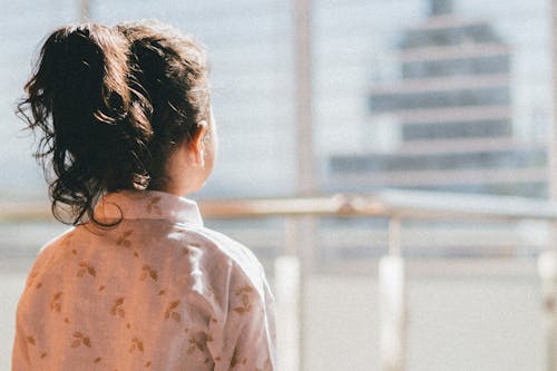 Small Girl Standing on the Balcony Looking at the City