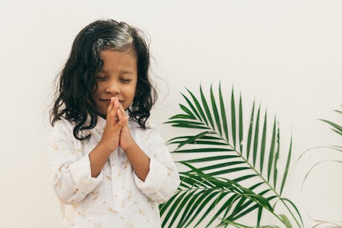 Cute Young Girl Praying next to a Plant