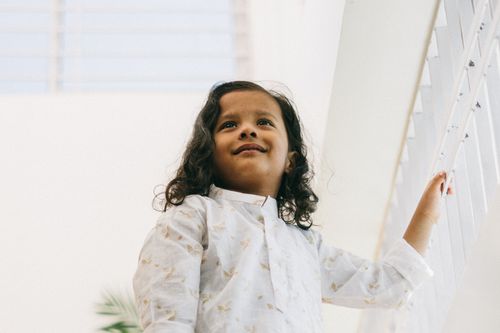 Free A cheerful child in a white shirt looking up, captured indoors with soft lighting. Stock Photo