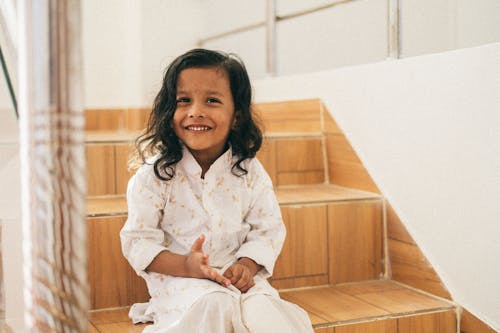 Smiling Girl in Shirt Sitting on Stairs