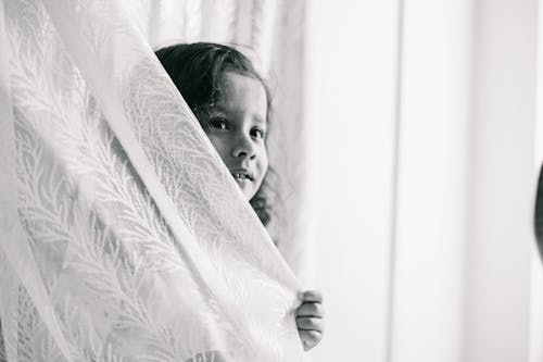 Young Girl Hiding Behind a Curtain