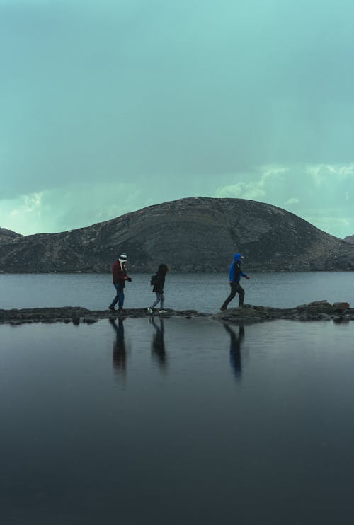 People Hiking on Rocks on Lake
