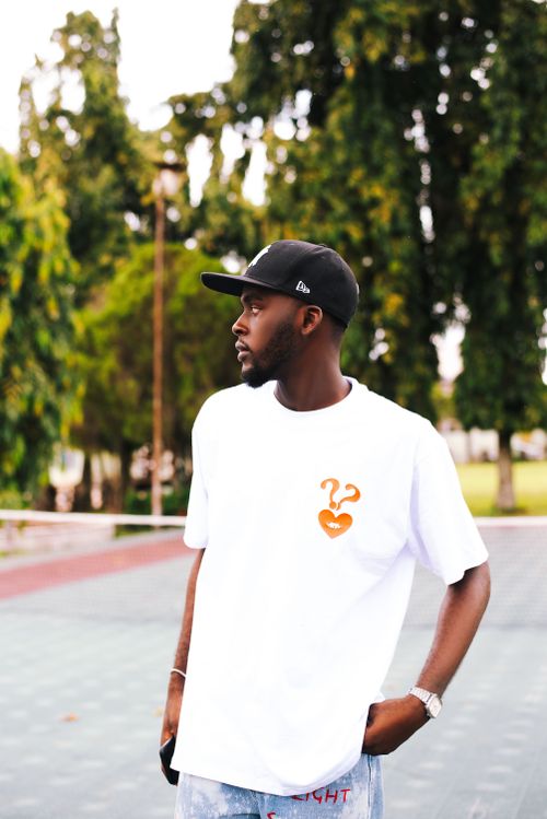 Free Young man with cap in casual summer outfit stands outdoors, exuding urban style. Stock Photo