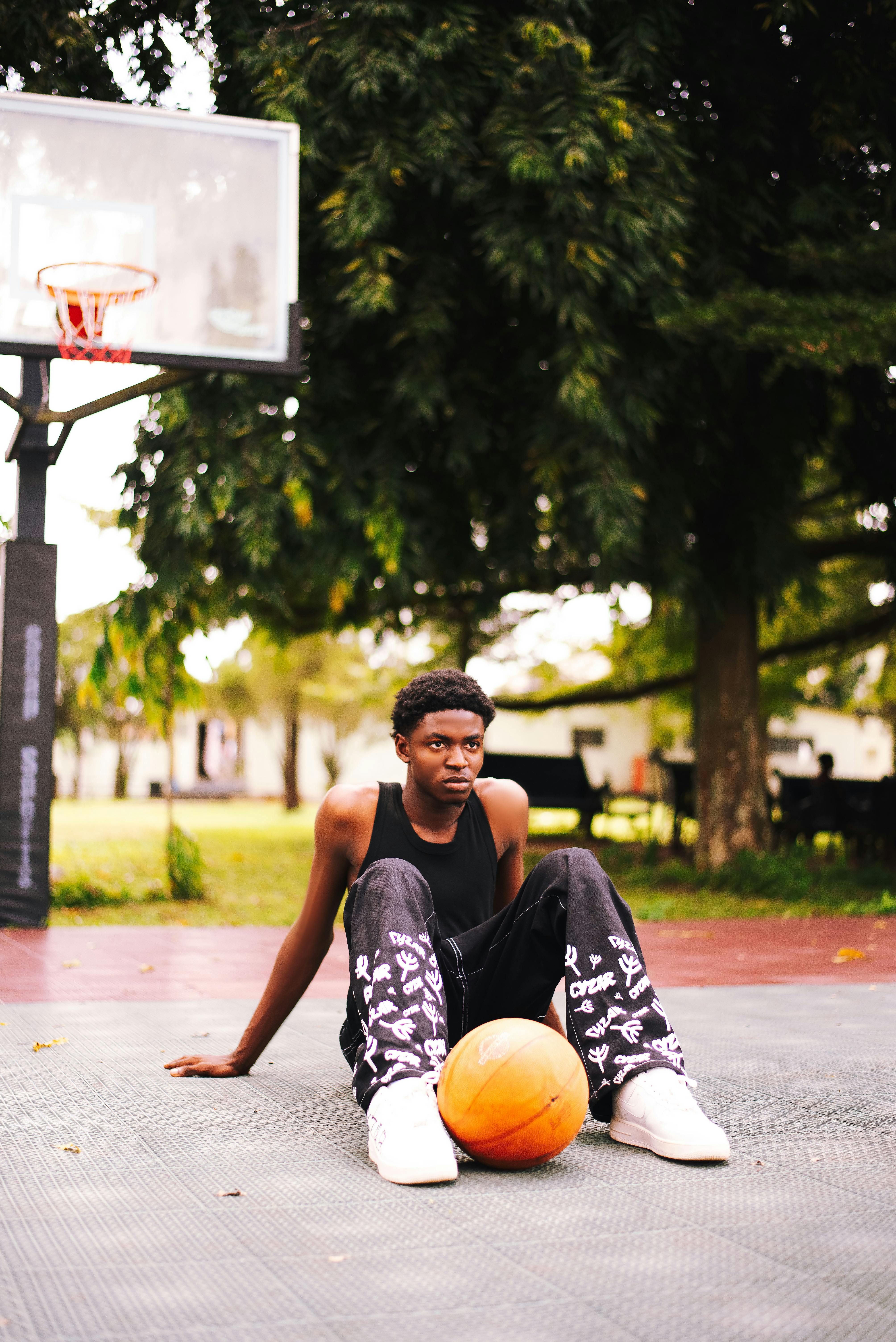 young man sitting on the ground at a basketball court