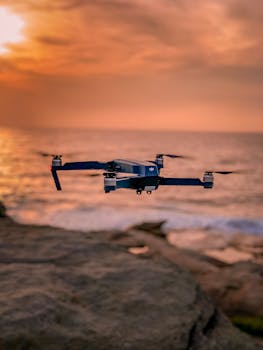 在日落时分，一架无人机盘旋在岩石海岸线上，营造出宁静而令人惊叹的氛围