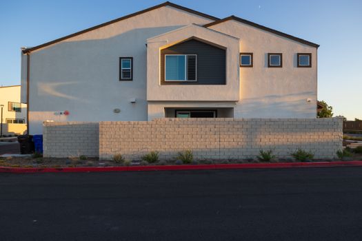 Front view of a modern house with a brick wall and minimalistic design under clear skies.