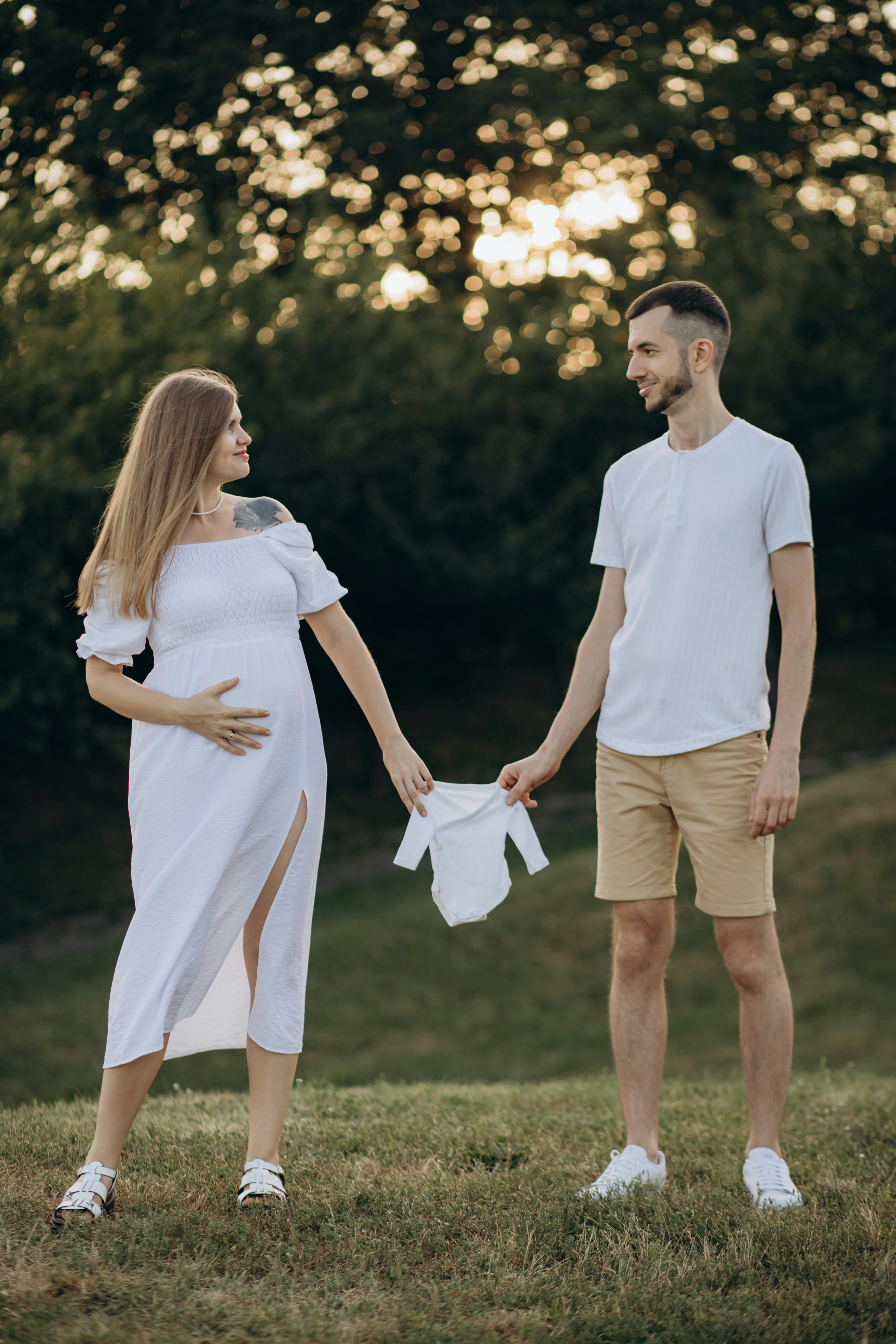 Image of Mother To Be Wife Holding Her Belly By Both Hands, Father Stay  Behind And Gives Thumbs-Up Gesture, Happy Couple Posing For A Photo Outdoor  Evening Time, Couple Goals Concept,-VE620575-Picxy